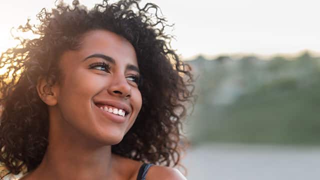 a woman smiling outdoor while looking out to the horizon