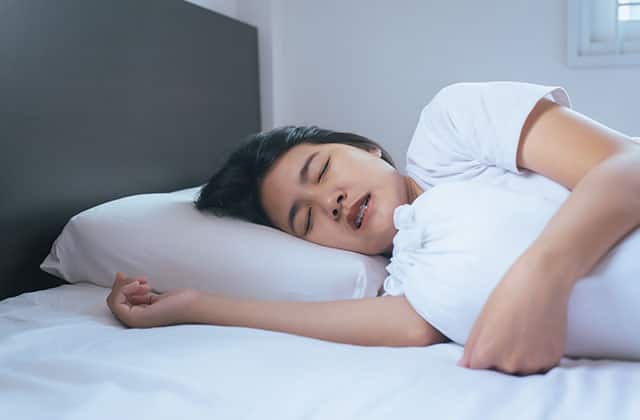 A young woman is sleeping in a bed