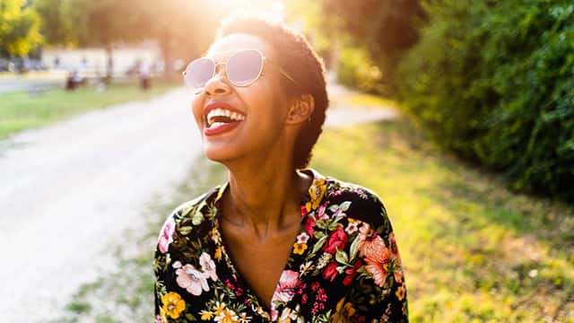 A woman is smiling outdoors
