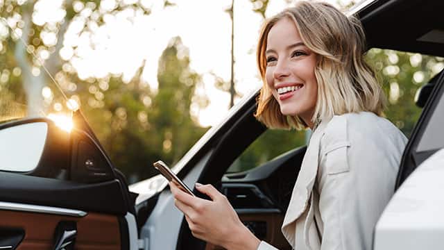 A beautiful businesslike woman sitting in car and using cellphone