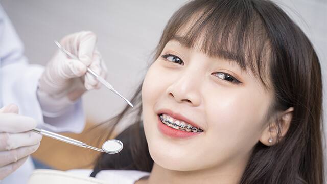 Teenage female with braces smiling in dentist chair