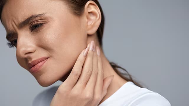 woman holding her jaw in pain