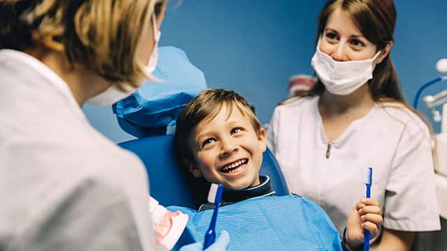 Dentist teaching a child to brush teeth.