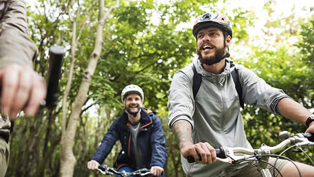 Young men riding bikes thru forrest 