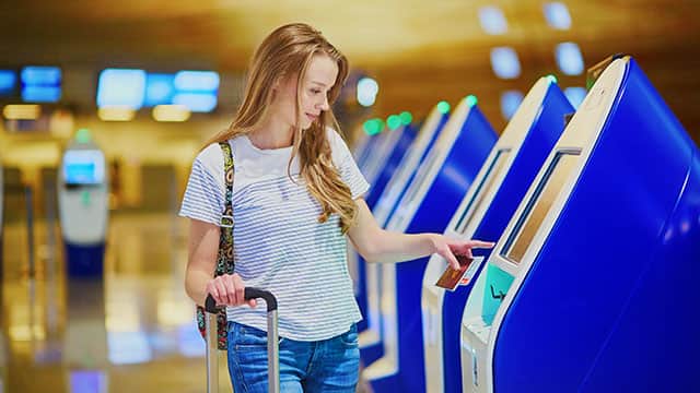 A woman using a self check-in machine at the airport