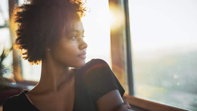 Young woman looks out the window of a restaurant on a sunny day 