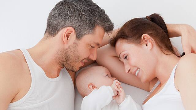 couple with baby lying between them
