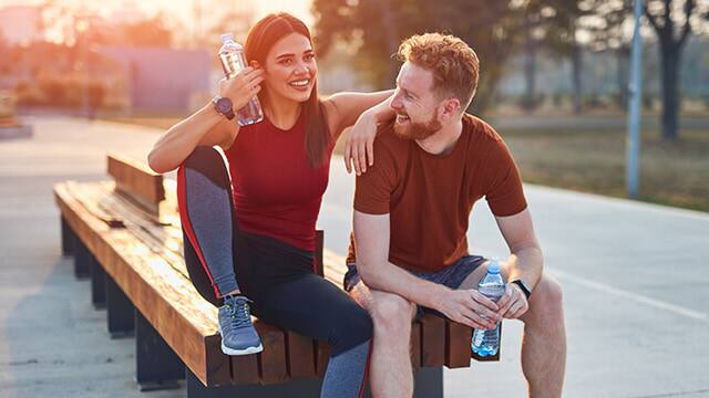 athletic couple taking a break on bench
