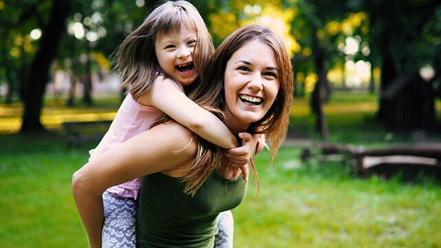 woman with child with down syndrome piggy back