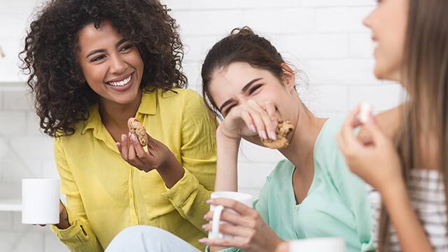 friends laughing eating cookies and coffee