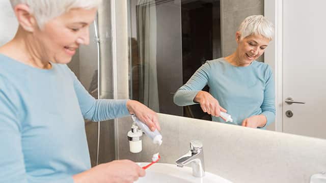 Woman putting toothpaste on a brush