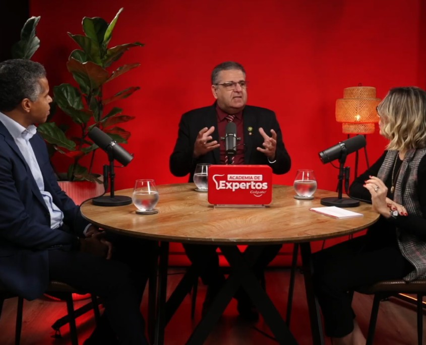 Innovación en Salud Bucal: Evidencia clínica para transformar la prevención. Tres panelistas conversando en el podcast Academia de Expertos Colgate con micrófonos en estudio de fondo rojo.