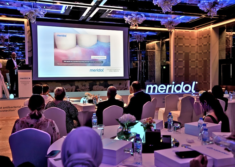 Grupo de personas reunidas viendo una presentacion de meridol en un salón
