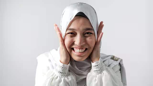 Une femme avec un foulard souriant et se tenant les joues