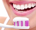 A close up of the toothpaste on toothbrush and woman's mouth