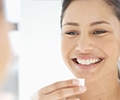 Woman smiling in mirror holding mouthwash