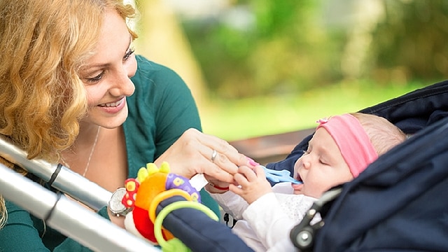 a mom is using a teething toy for her teething baby