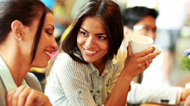 two woman chatting while enjoying a cup of coffee
