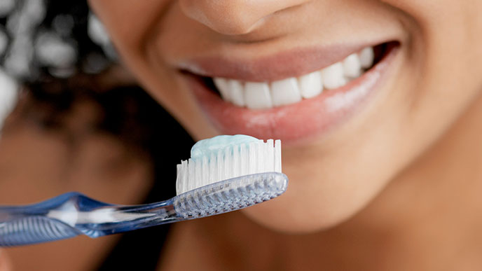 Close-up of a young woman smiling while brushing her teeth