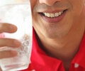 A close up of the man holding a glass with sparkling water and ice
