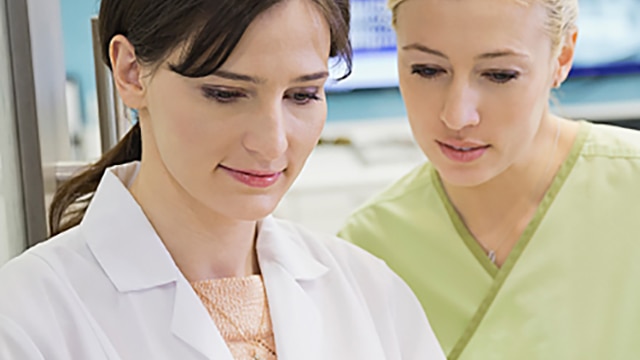 Nurse in green scrubs looking over dentists shoulders