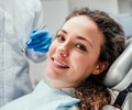 Smiling young woman receiving dental checkup. 