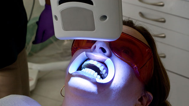 Una paciente está en blanqueamiento dental UV en un consultorio