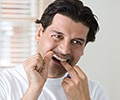 A man is flossing teeth in a bathroom