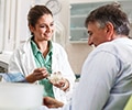 A female dentist in dental office talking with a senior male patient and preparing for a treatment