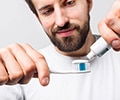 A close up of a man holding a toothbrush with toothpaste on it