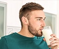 A young man drinking milk from a glass at home