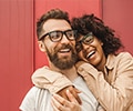 A happy young couple in eyeglasses smiling and hugging on the street