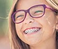 Young girl in purple glasses smiling with braces