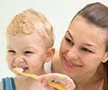 A mother teaching a child teeth brushing in a bathroom