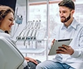 A male dentist showing a tablet to a female patient at the dental office