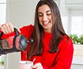 Young  woman making morning coffee and smiling