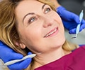 An older woman is at the dentist receiving a dental procedure