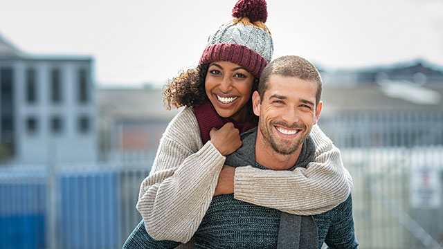 A couple is smiling outdoors