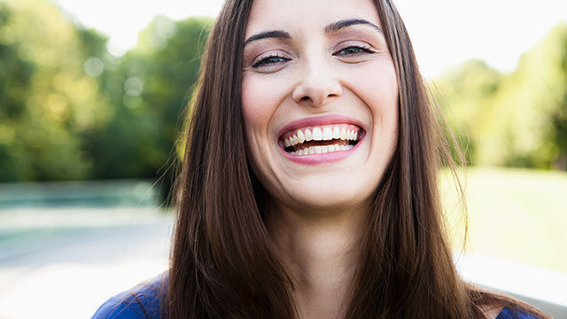 A young woman is laughing outdoors