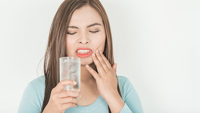 Una mujer con sensibilidad dental bebiendo agua fría