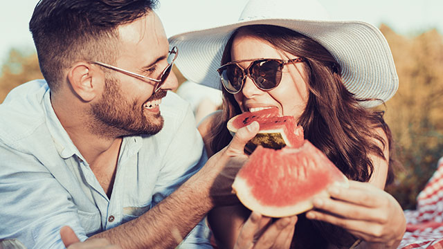 A couple eating a watermelon outdoors
