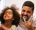 Father and daughter are brushing their teeth over the sink