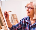 Elderly woman painting in her home