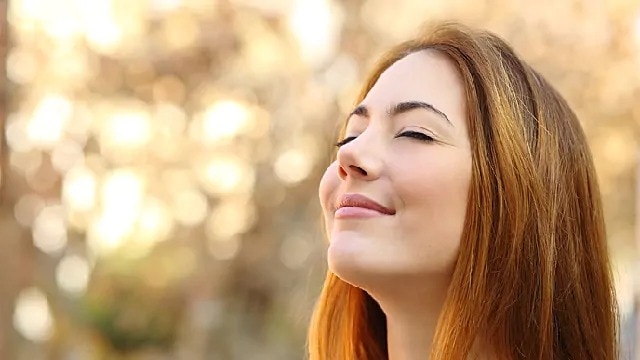 a woman smiling with her eyes closed enjoying the outdoor