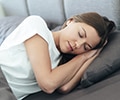 woman sleeping on a grey pillow on the couch 