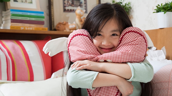 young girl smiling hugging a pillow