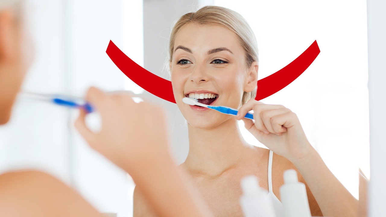 Woman brushing her teeth in front of a mirror