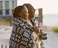Senior couple wrapped in blanket on the beach
