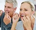 close-up of an older couple flossing their teeth in the bathroom