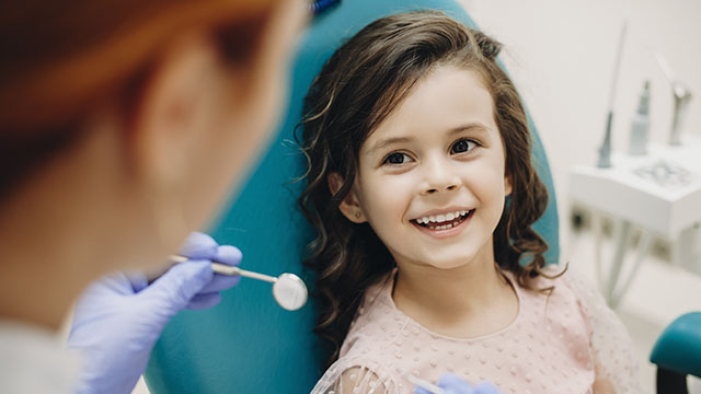 Petit enfant souriant en parlant avec le dentiste pédiatrique après son dixième examen en somatologie pédiatrique
